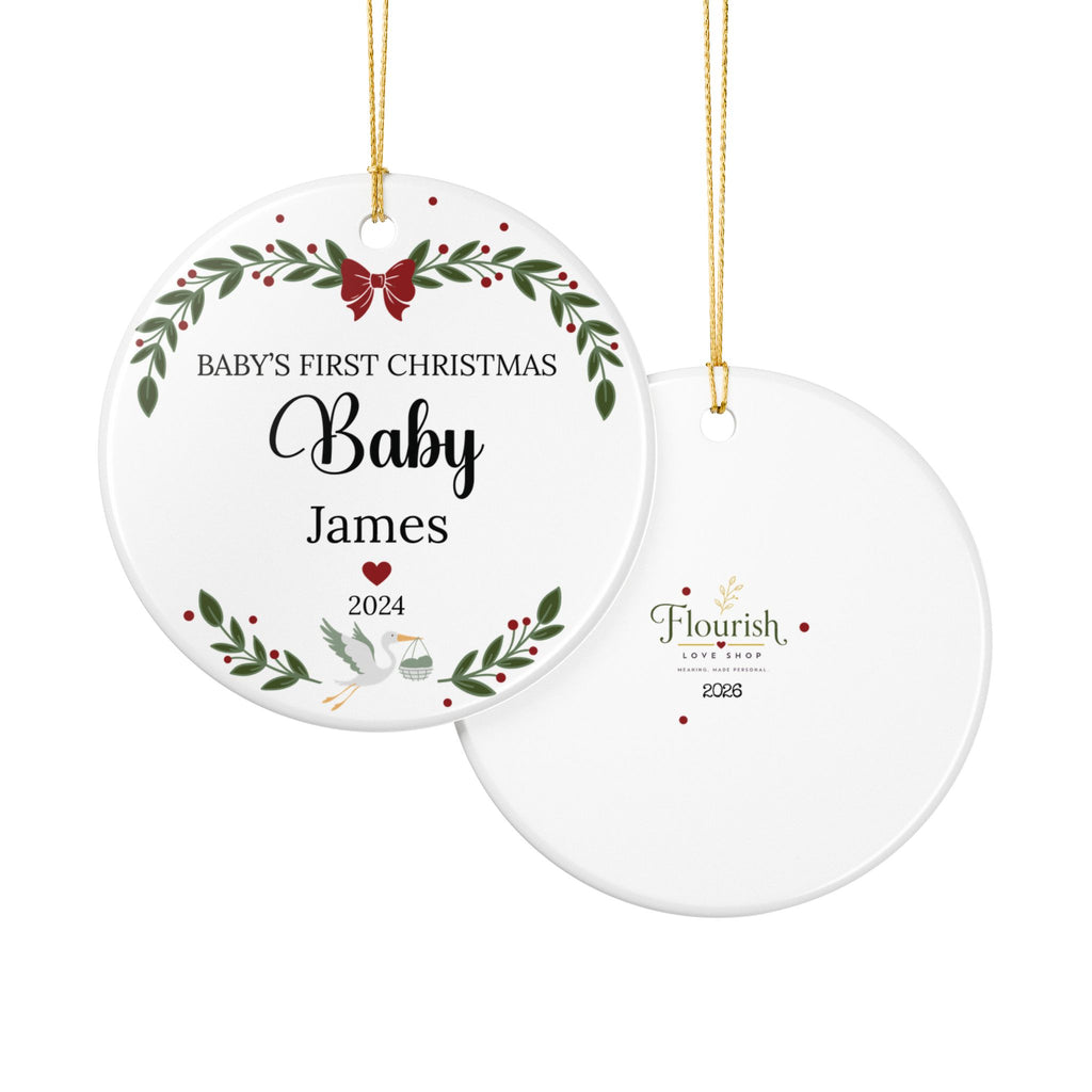 Two round hanging Christmas ornaments shown on a white background. The front ornament is white with a green wreath, red bow and berries, and the text 'BABY'S FIRST CHRISTMAS Baby James 2024'.