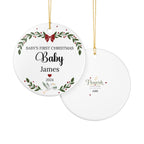 Two round hanging Christmas ornaments shown on a white background. The front ornament is white with a green wreath, red bow and berries, and the text 'BABY'S FIRST CHRISTMAS Baby James 2024'.