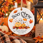 A round white ceramic Halloween ornament hanging from a string, printed with the words 'Boo Crew' and a cute illustration of four playful ghosts and pumpkins on autumn leaves. The ornament is personalized with the names 'Will, Dan, Grace, Alex' and a phrase starting with 'since 2022'.