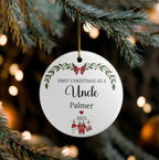 A round white ceramic Christmas ornament hanging from a pine branch. The ornament is personalized with the text 'FIRST CHRISTMAS AS A Uncle Palmer' and the year '2025', decorated with red and green holiday illustrations including a Santa Claus and stockings.