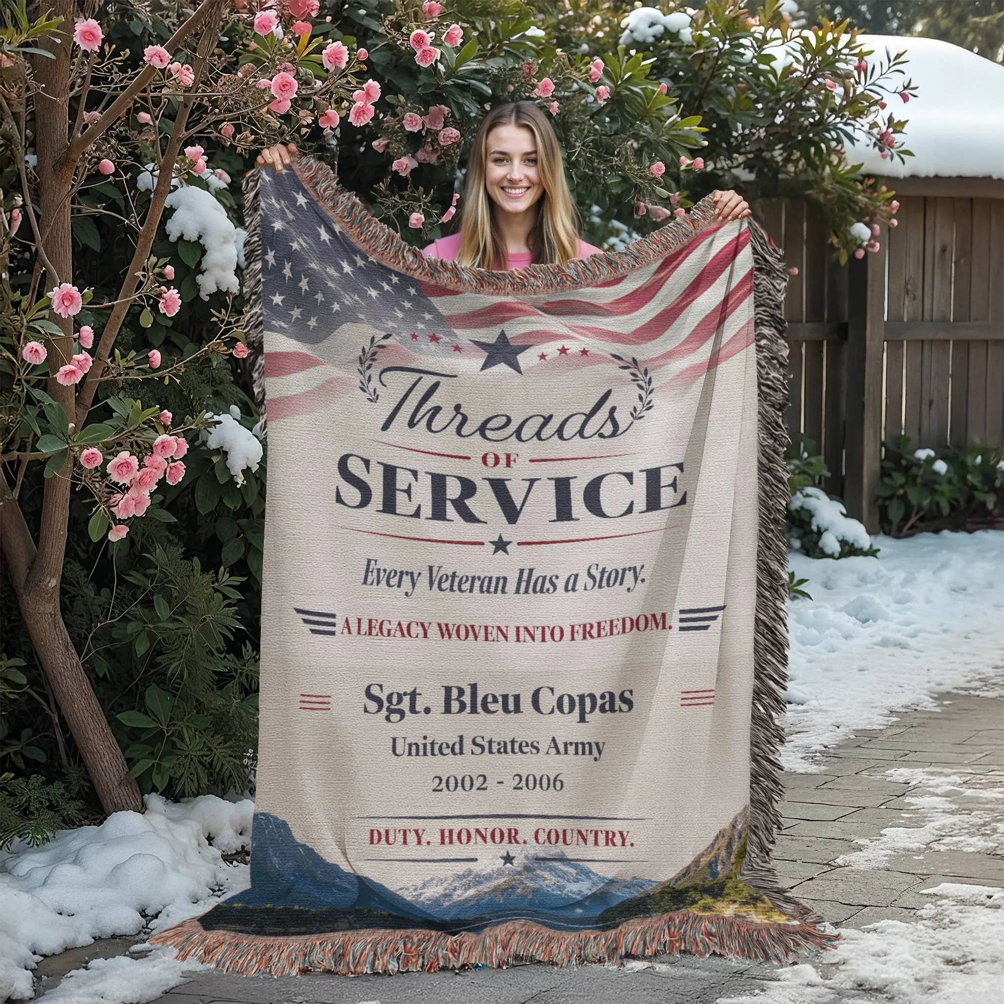 A person is holding a 'Threads of Service' veteran-themed blanket that features text and an American flag design.