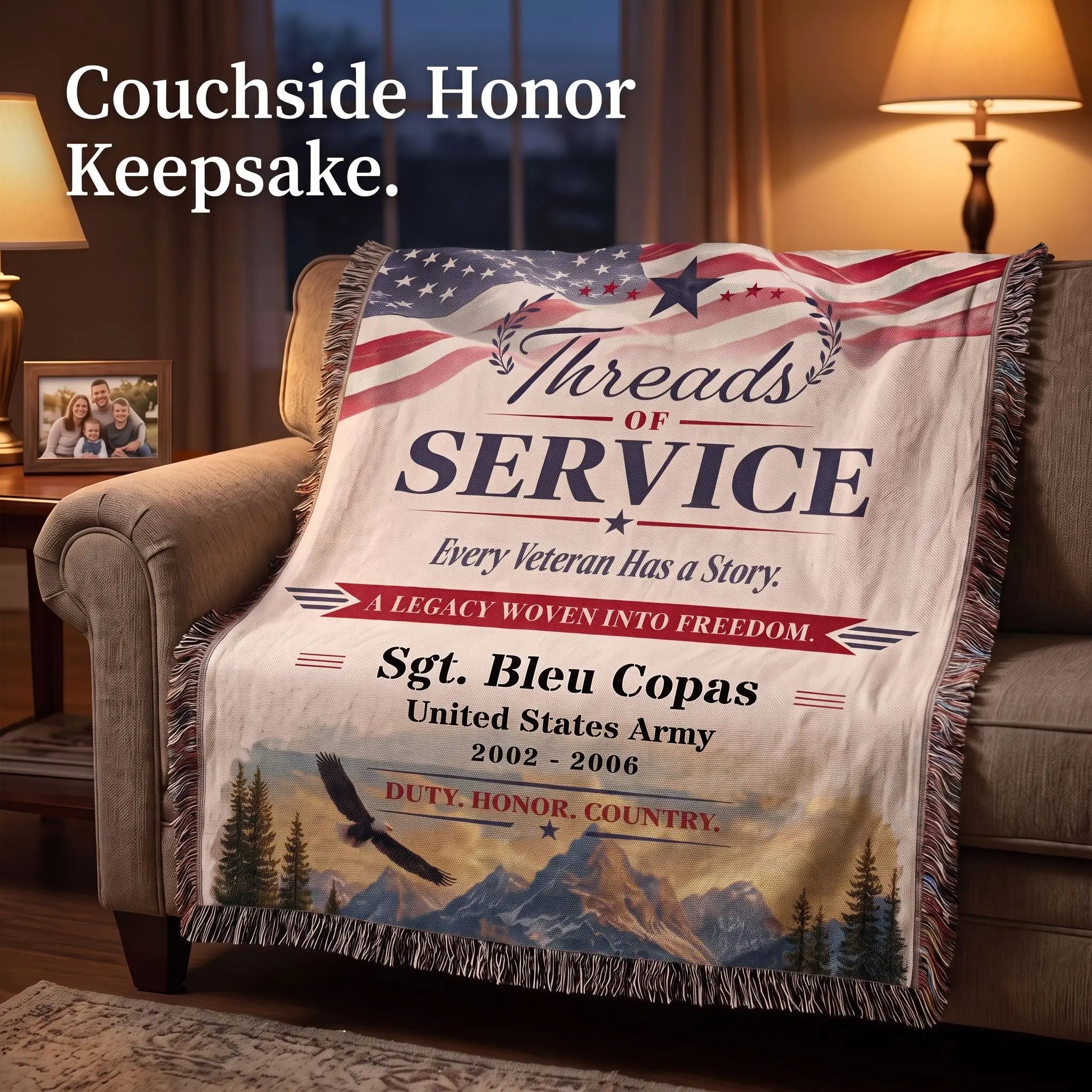 A personalized veteran keepsake throw blanket draped over a couch in a warmly lit living room. The blanket features a printed American flag at the top, the words 'Threads of Service,' a red banner reading 'A Legacy Woven into Freedom,' and a mountain-and-eagle scenic design with the text 'Sgt.