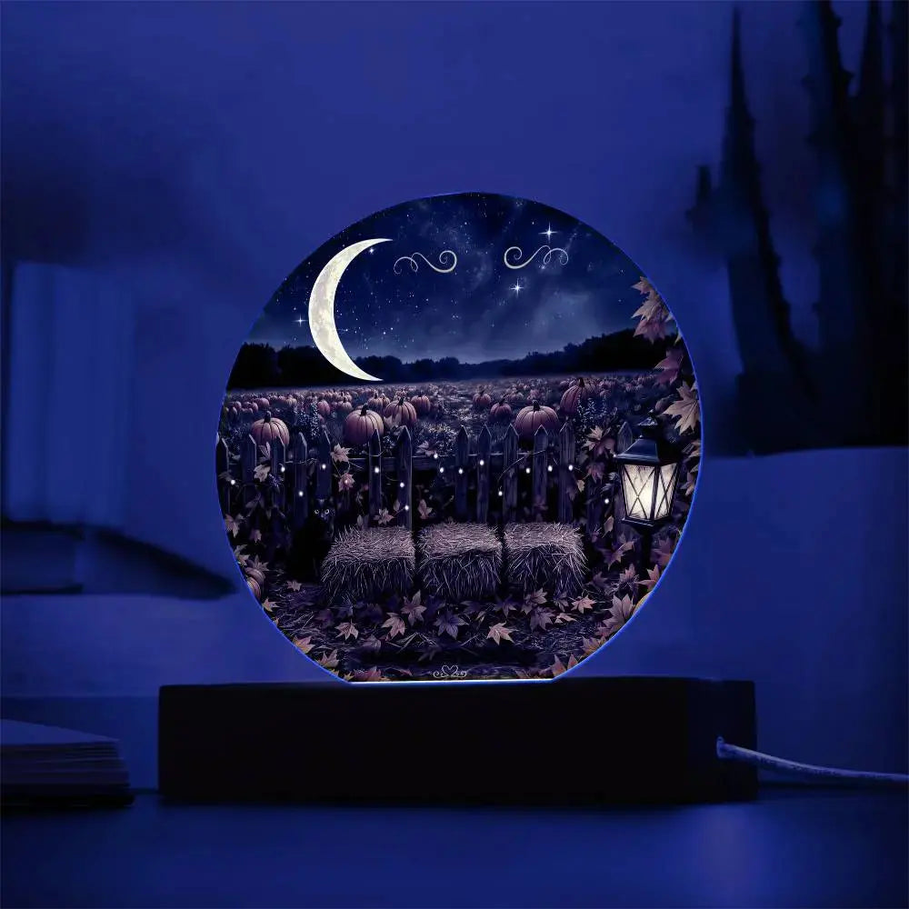 Round acrylic plaque featuring a moonlit pumpkin patch, hay bales, and a glowing lantern on a black light-up base.